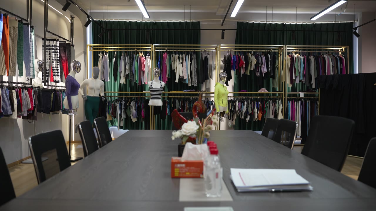 Meeting table in a garment sample room with racks of activewear references