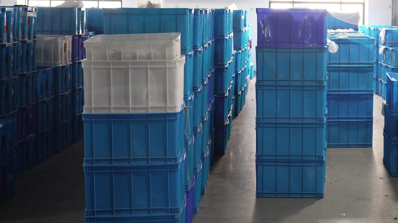Stacked blue, white and purple storage bins in a warehouse aisle