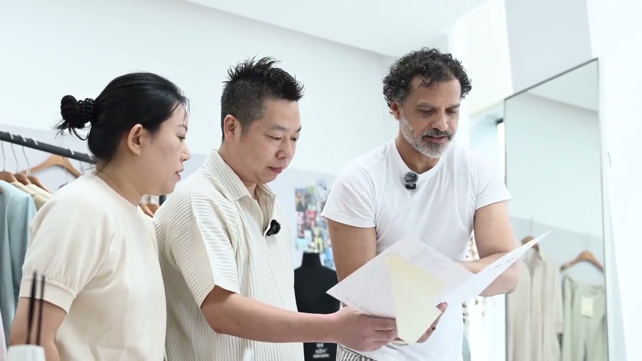 Three people discussing product documents at a table in supplied footage