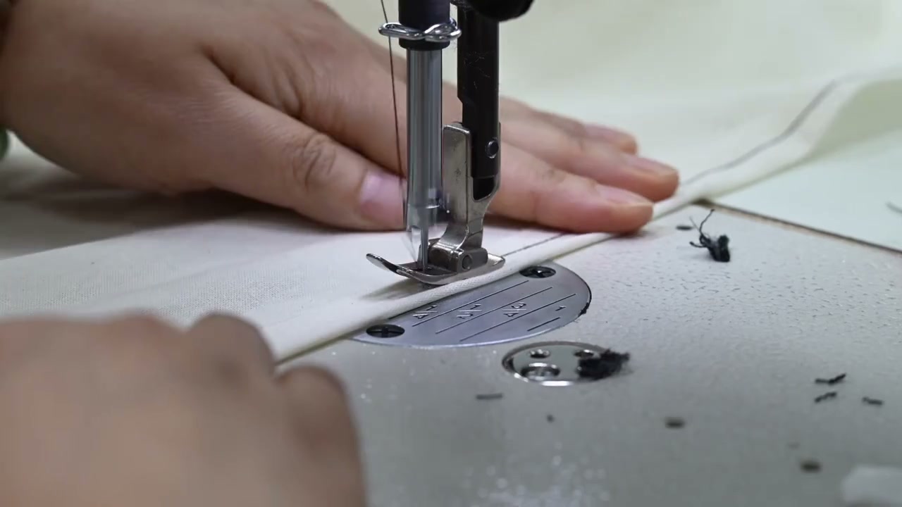 Close view of a garment seam being sewn in supplied process footage